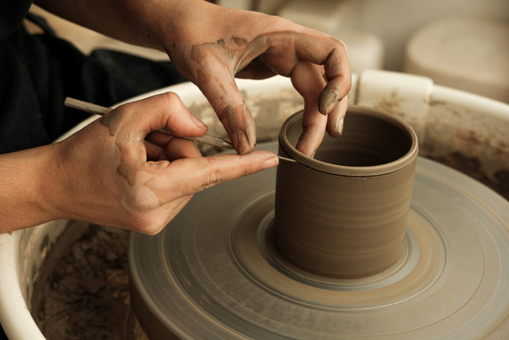 Mãos moldando argila em uma roda de oleiro, capturando o processo artesanal da cerâmica em um estúdio de trabalho.